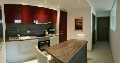 a kitchen with red cabinets and a wooden table at Ferienwohnungen Sammer in Strobl