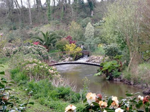 a bridge over a river in a garden at Appartement dans gîte vue mer et campagne in Sibiril