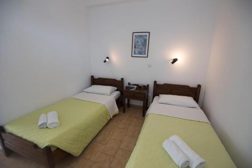 a room with two beds and a night stand with a table at Katerina Rooms in Naousa