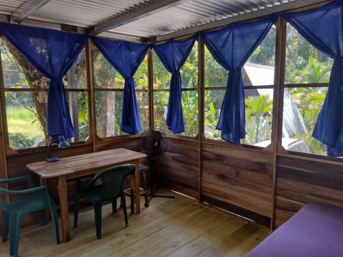 a room with a table and chairs and windows at Arboura Eco Cabins in Uvita