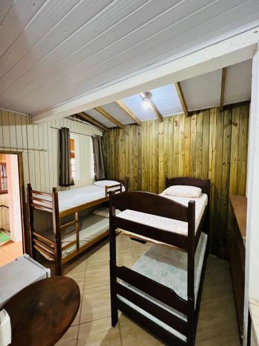 a room with three bunk beds and a table at Pousada Rosa Center in Praia do Rosa