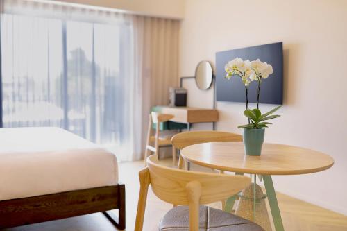 a bedroom with a bed and a table with a vase of flowers at Hyatt House Johannesburg Rosebank in Johannesburg