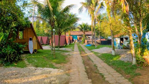 a dirt road with a house and palm trees at BASE CAMP, Guest House, Surf House , Itamambuca, Ubatuba in Ubatuba