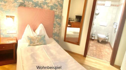 a bedroom with a bed with a mirror and a bathroom at Hotel Goldener Ochs in Bad Ischl