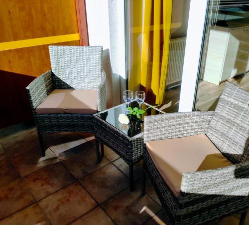 two chairs and a table with wine glasses on it at Apartma MAX in Moravske-Toplice