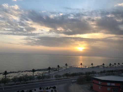 a sunset over the ocean with palm trees and a road at квартира с красивым видом на море in Aktau
