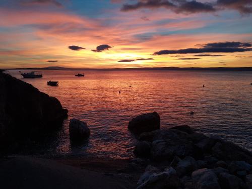a sunset over a body of water with rocks at Luxusvilla Marim in Stara Baška