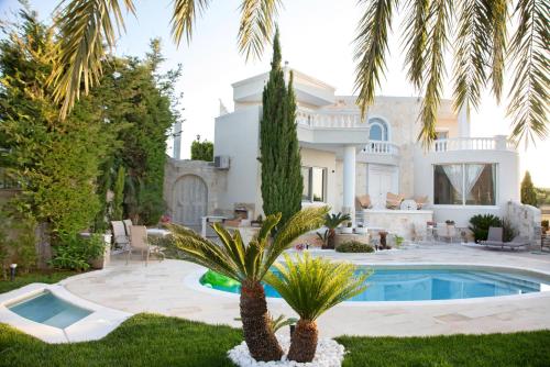 a villa with a swimming pool and palm trees at Villa Kokalis Resort hotel in Gouves