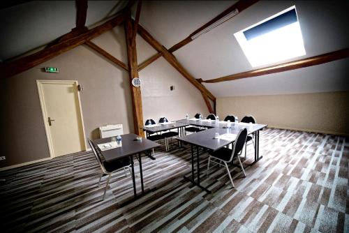 a meeting room with tables and chairs in a building at Logis Auberge Des Moissons in Matougues