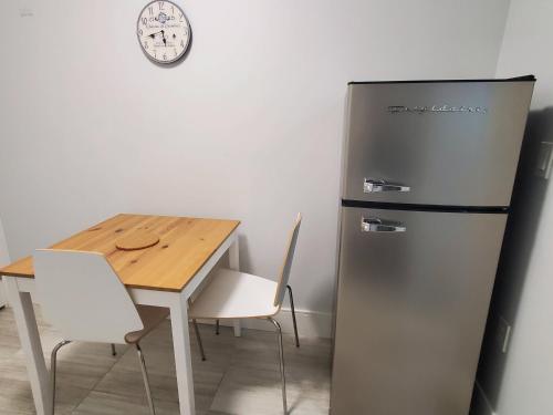 a kitchen with a refrigerator and a table and a clock at Cozy Guest Suite in Quiet Home with Private Entry in Vancouver
