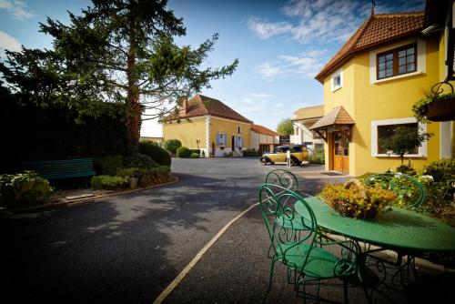 a green table and chairs in front of a house at Logis Auberge Des Moissons in Matougues