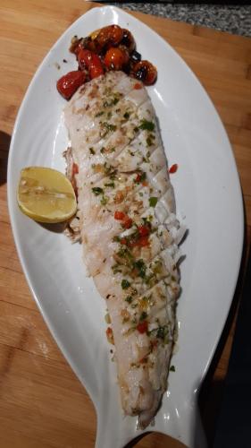 a white plate with a piece of fish and a lemon at Che Cauquen in Puerto Santa Cruz