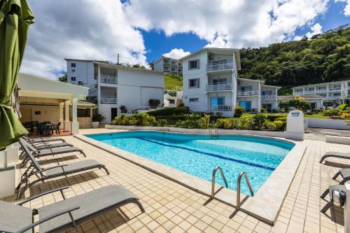 a swimming pool with chairs and a building at Siesta Hotel in Morne Rouge