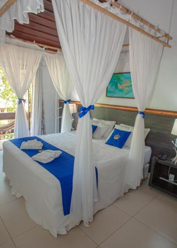 a bedroom with a bed with white drapes at Hotel Solar do Imperador in Porto Seguro