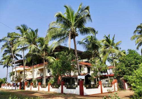 a hotel with palm trees in front of it at SHANU'S SEASIDE INN - A Guesthouse, 100 metres to Candolim Beach in Candolim