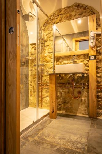 a shower in a bathroom with a stone wall at La Rondine in Tagliacozzo