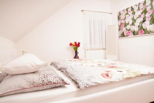 Un dormitorio blanco con una cama con flores. en gemütliche Wohnung in Hohenems en Hohenems