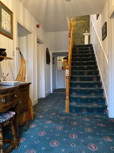 a hallway with a staircase in a house with a piano at Garden Park Guest House in Grantown on Spey