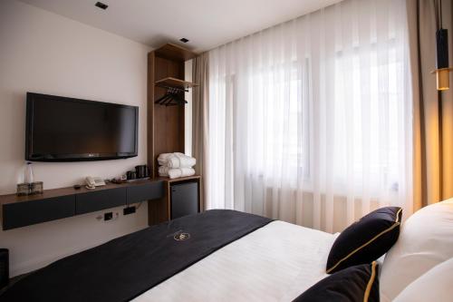 a hotel room with a bed and a flat screen tv at Plaza Boutique Hotel in Prishtinë