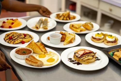 a table with plates of breakfast food on it at Siesta Hotel in Morne Rouge