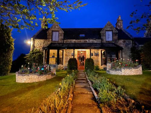a house with flowers in front of it at night at Garden Park Guest House in Grantown on Spey