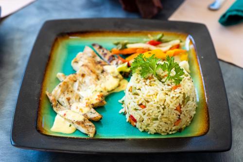 a plate of food with rice and vegetables at Siesta Hotel in Morne Rouge