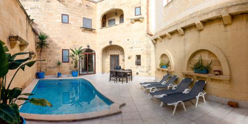 a patio with a pool and chairs and a table at Ta Gorga Holiday Farmhouse with Private Pool in Xewkija