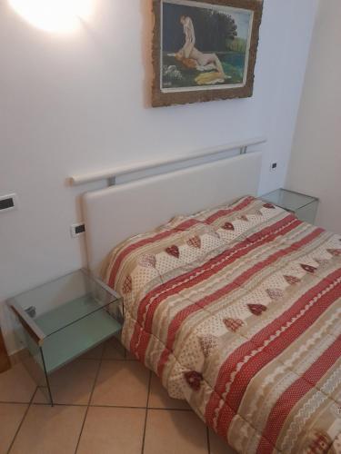 a bed with a quilt and a table next to it at Riva Apartment Negrelli in Riva del Garda