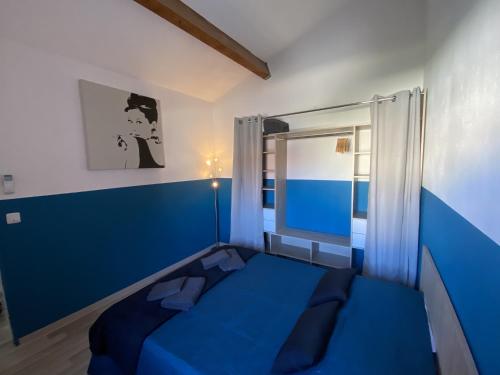 a blue bed in a room with a window at La Villa de la Plage in Argelès-sur-Mer