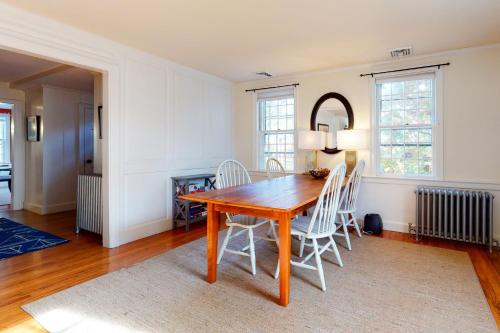 a dining room with a wooden table and white chairs at Pleasant Bay Retreat in Orleans