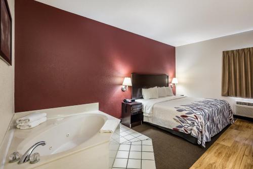 a hotel room with a bed and a bath tub at Red Roof Inn St Louis - Troy, IL in Troy