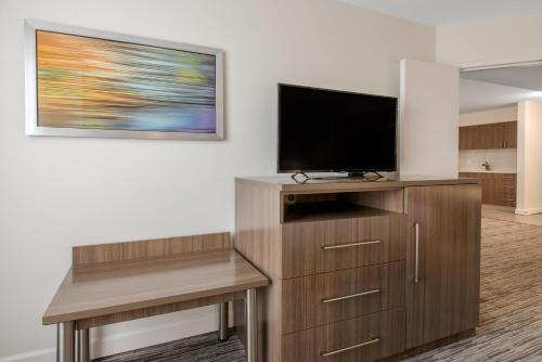 a living room with a flat screen tv on a wooden entertainment center at Holiday Inn Melbourne-Viera Conference Ctr by IHG in Melbourne