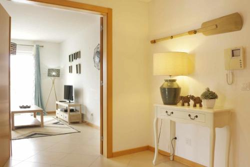 un soggiorno con tavolo e lampada sopra di Apartamento AzulMar Cabanas Gardens by Your Home Algarve a Armação da Abóbora