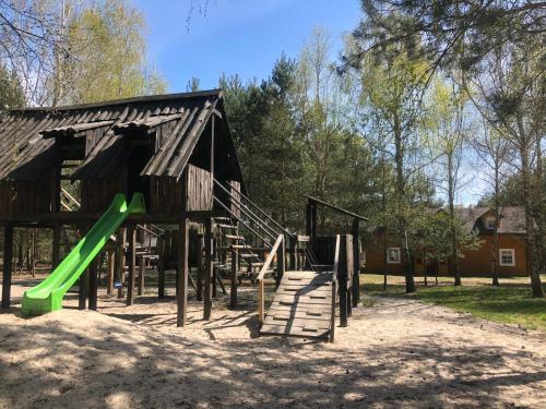 a playground with a green slide and a building at Dolina Bobrów in Siennica