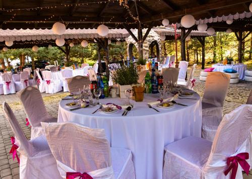 a table with white table cloths and chairs with plates and glasses at Dolina Bobrów in Siennica