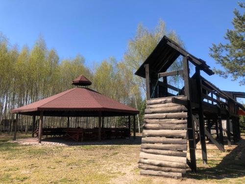 a wooden gazebo with a roof in a field at Dolina Bobrów in Siennica