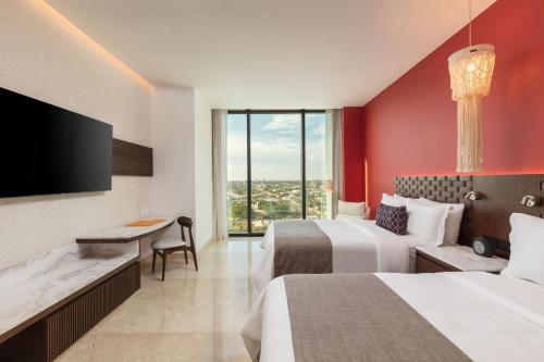 a hotel room with two beds and a flat screen tv at Camino Real Mérida in Mérida