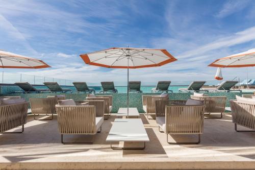 a patio with chairs and umbrellas and the ocean at Camino Real Mérida in Mérida