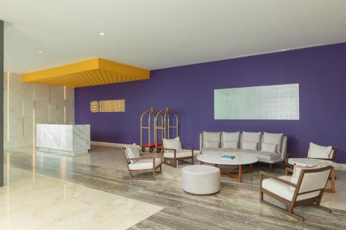 a lobby with a purple wall and chairs and a table at Camino Real Mérida in Mérida