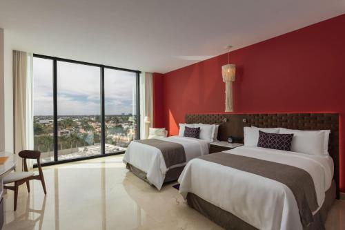 a hotel room with two beds and a red wall at Camino Real Mérida in Mérida