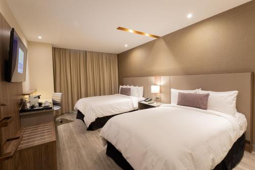 a hotel room with two beds and a television at Camino Real Fashion Drive Monterrey in Monterrey