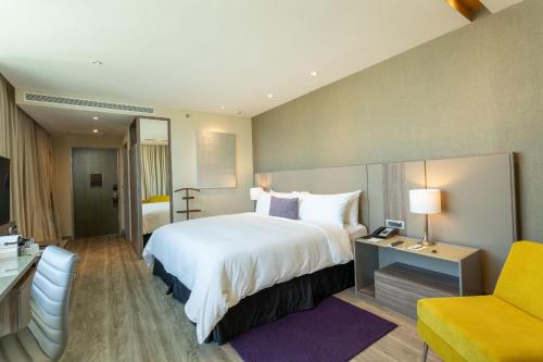 a hotel room with a large bed and a yellow chair at Camino Real Fashion Drive Monterrey in Monterrey