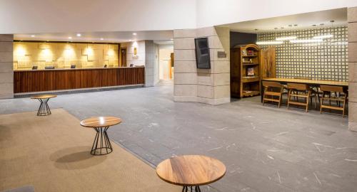 a lobby with tables and chairs and a bar at Camino Real Puebla Angelopolis in Puebla
