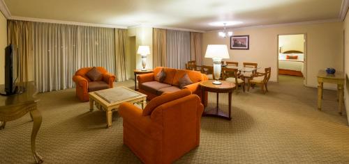a living room with orange furniture and a dining room at Camino Real Puebla Angelopolis in Puebla