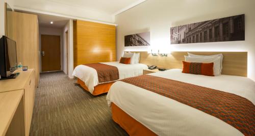 a hotel room with two beds and a flat screen tv at Camino Real Puebla Angelopolis in Puebla