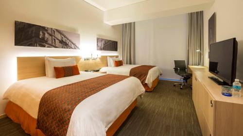 a hotel room with two beds and a flat screen tv at Camino Real Puebla Angelopolis in Puebla