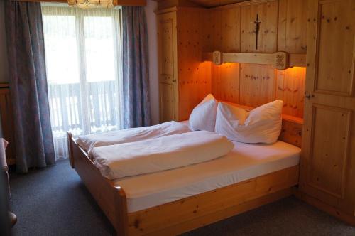 Bett in einem Holzzimmer mit Fenster in der Unterkunft Haus Tiroler Heimat in Nauders