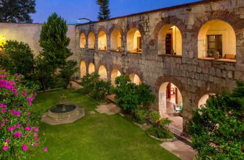 an old stone building with a garden and a fountain at Quinta Real Oaxaca in Oaxaca City