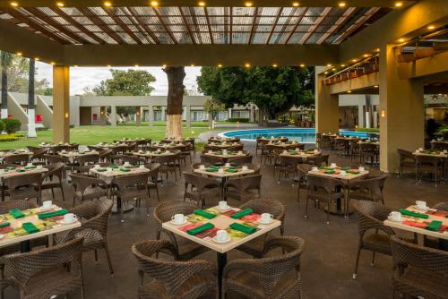 a restaurant with tables and chairs and a pool at Camino Real Guadalajara in Guadalajara