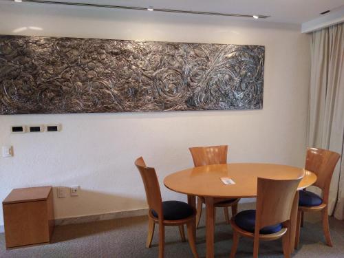 a table and chairs in a room with a painting on the wall at Camino Real Guadalajara in Guadalajara